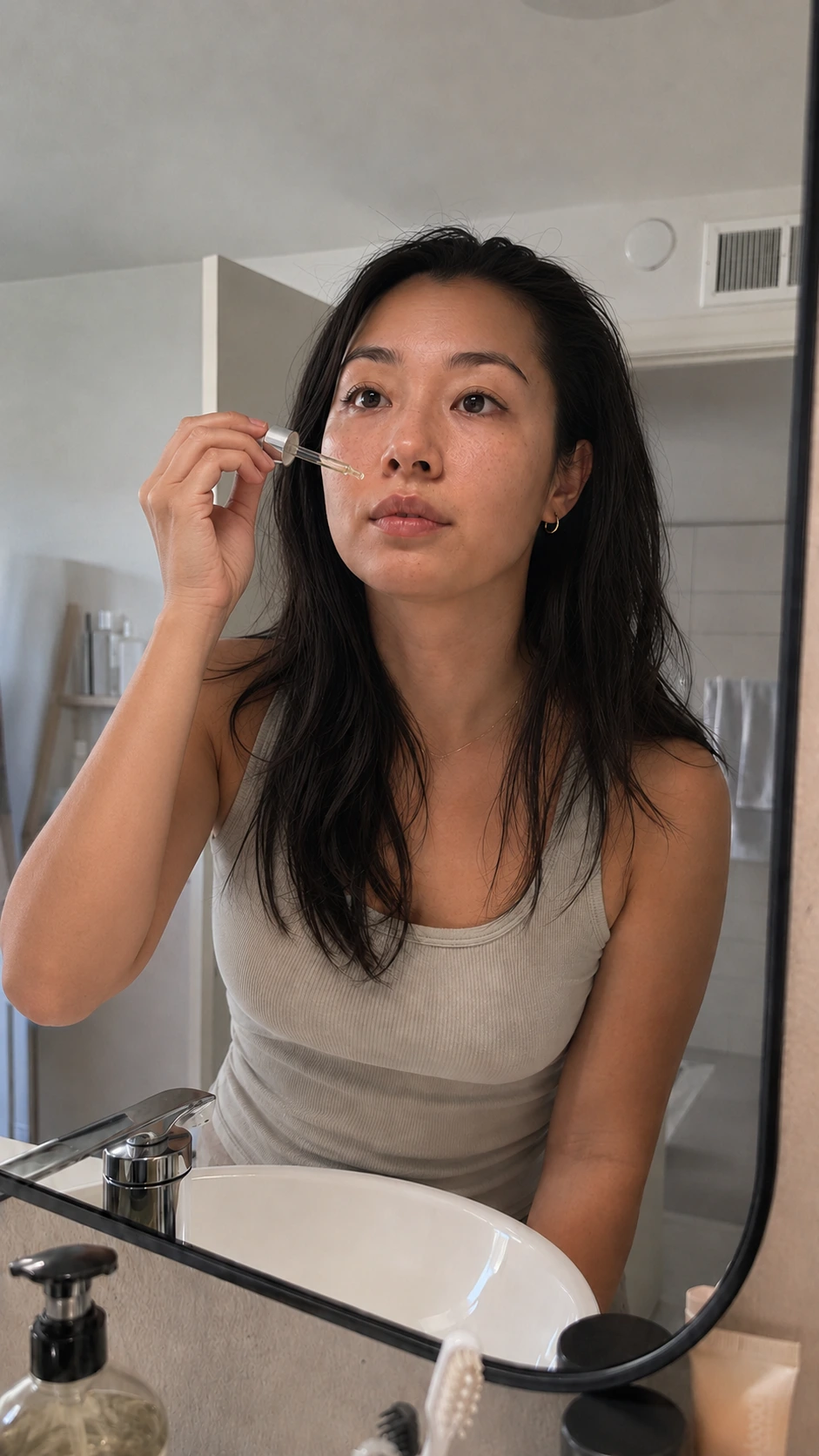 Reference image of the model applying a drop of serum near her face